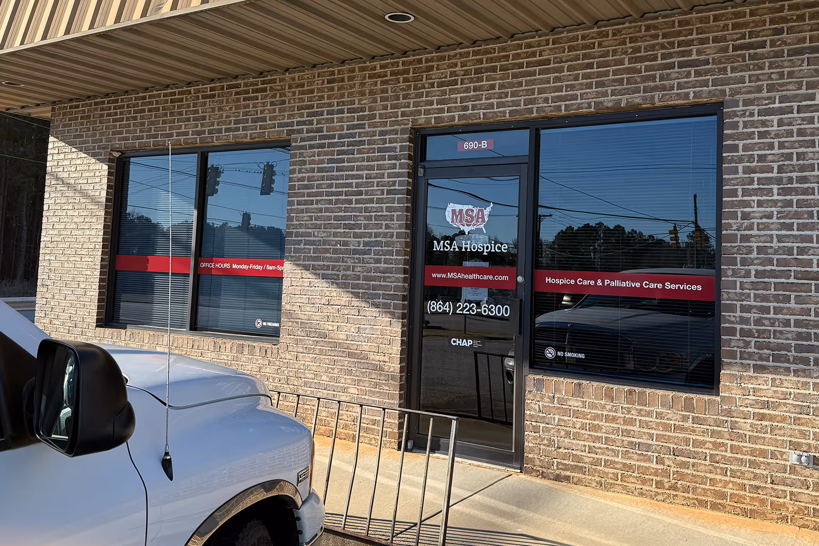 Brick exterior of MSA Hospice clinic with glass door, windows, and a white pickup truck.