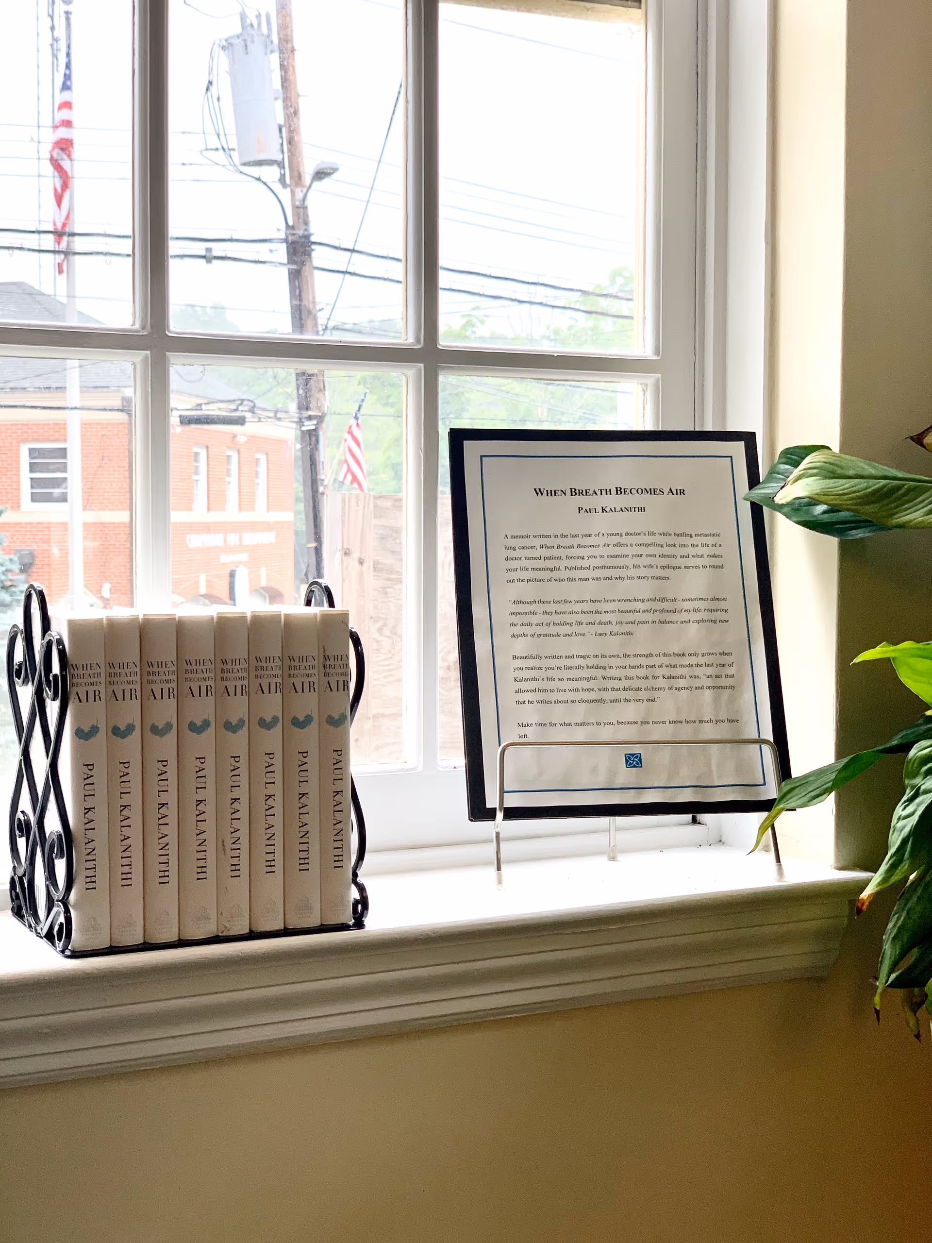 Window sill with white Paul Kalanithi books and a framed document.