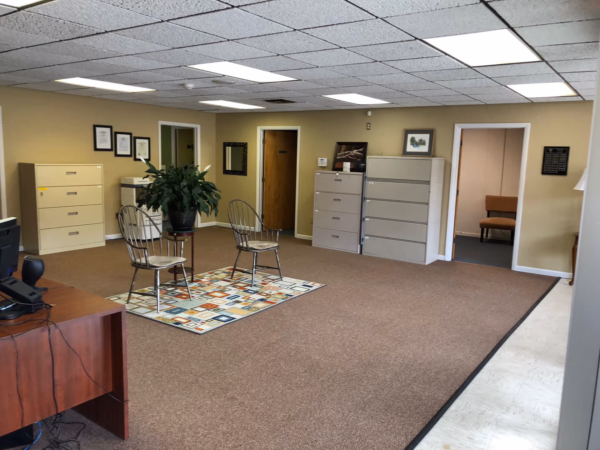 Lobby area of Comfort Keepers Home Care with chairs, plant, and filing cabinets.