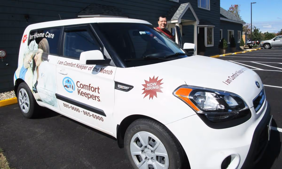 A white Comfort Keepers van parked outside a building with a person nearby.