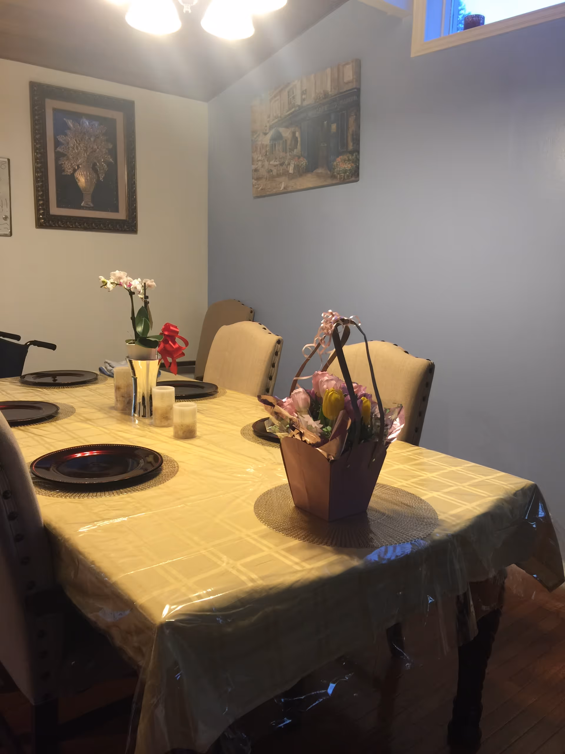 A dining room table set with plates and a flower centerpiece in a pale blue-walled room.