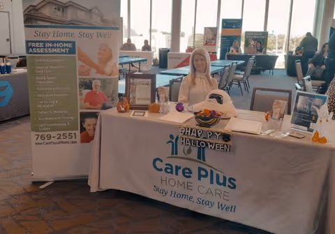 Care Plus Home Care booth with banners and a staff member at an indoor expo.