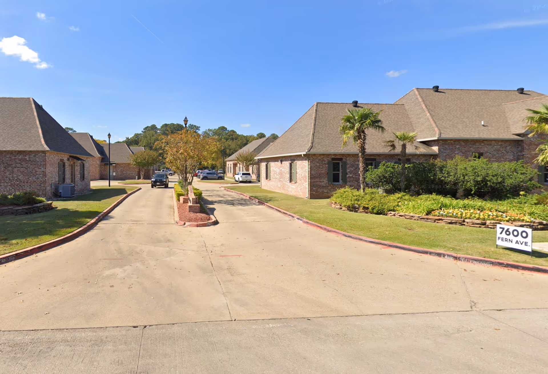 Wide view of a brick senior living facility exterior with a driveway and landscaped entrance.