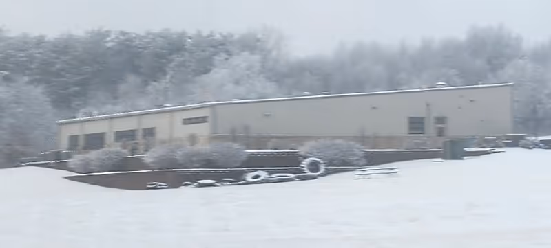 Snow-covered exterior of a low-rise medical center with shrubs and parking area.