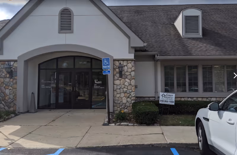 Front view of a Senior Helpers facility entrance with stone facade and handicap parking sign.