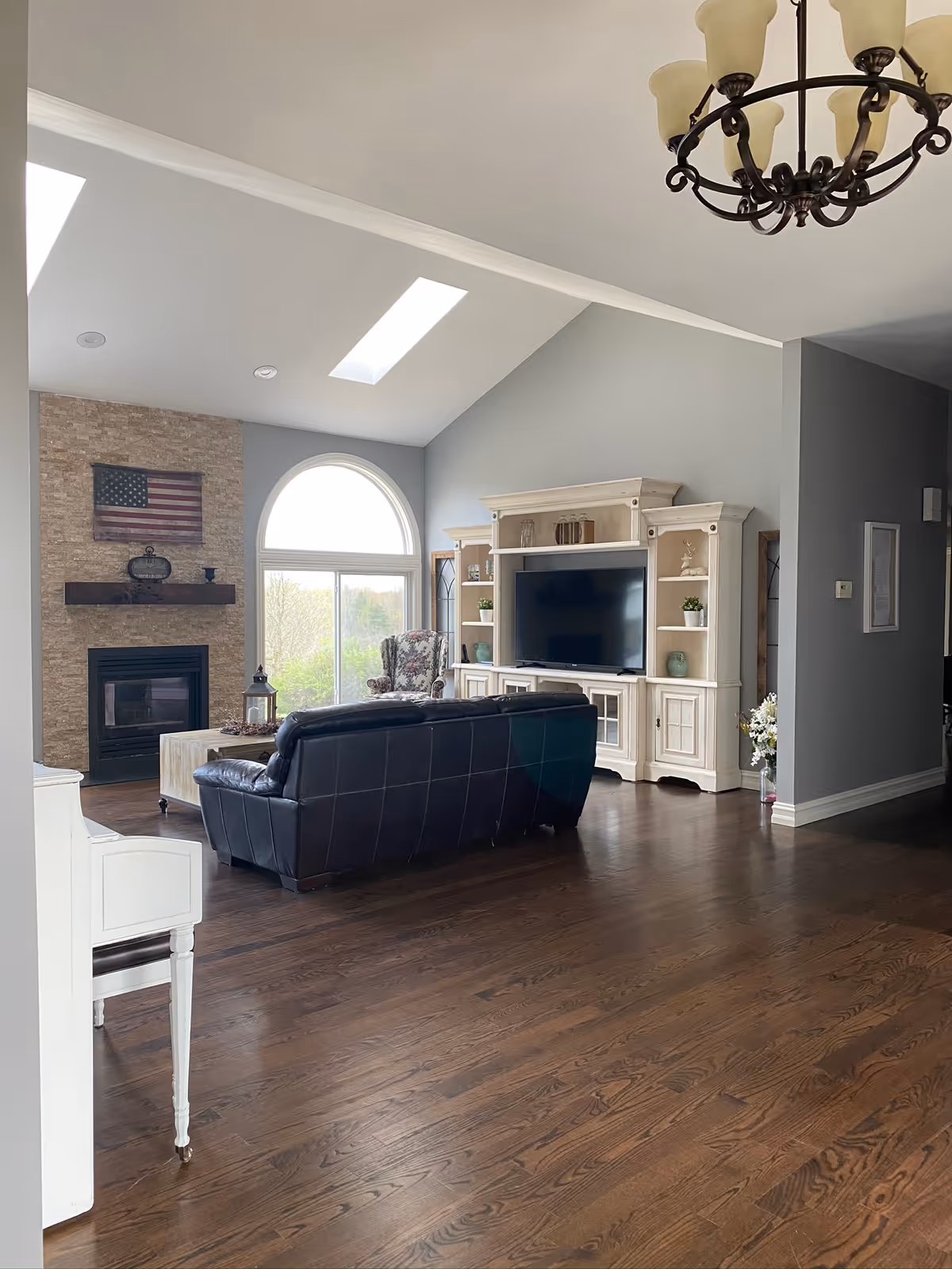 Bright living room in Addison-Oaks Manor with fireplace, leather sofa, and arched window.