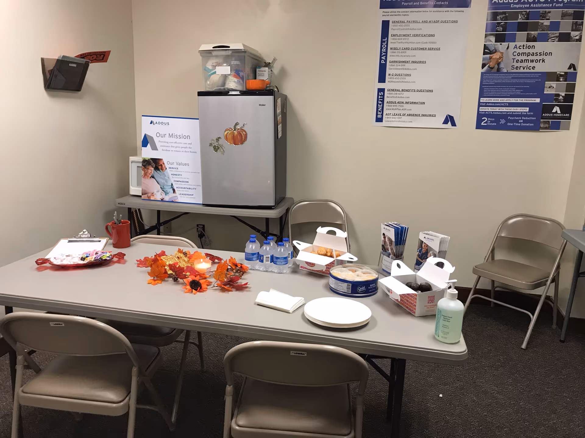 Long table set with snacks, water bottles, and napkins in a break room.