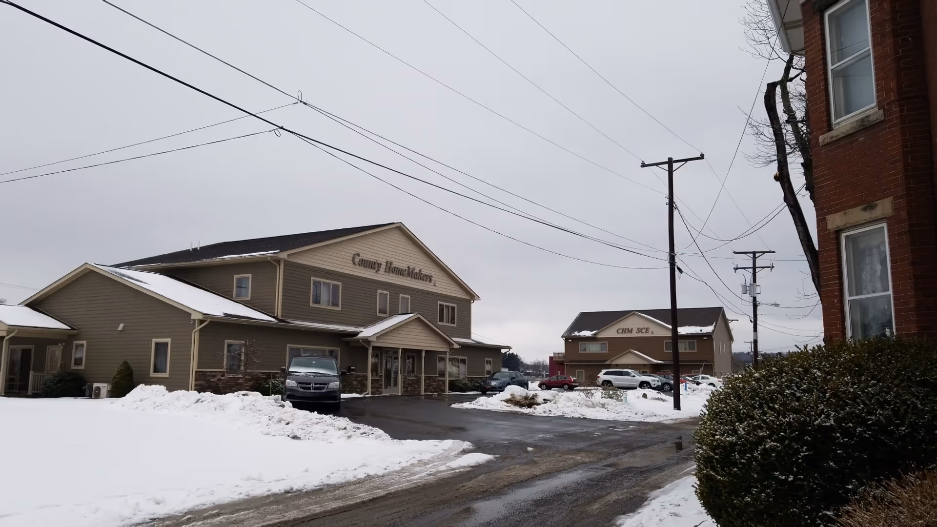 Snowy exterior of Arcadia Home Care Staffing buildings with parked cars.