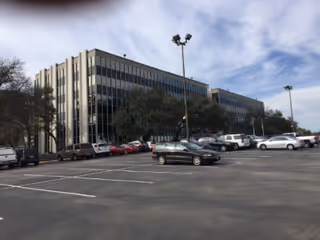 Exterior view of a modern building with a large parking lot in front.