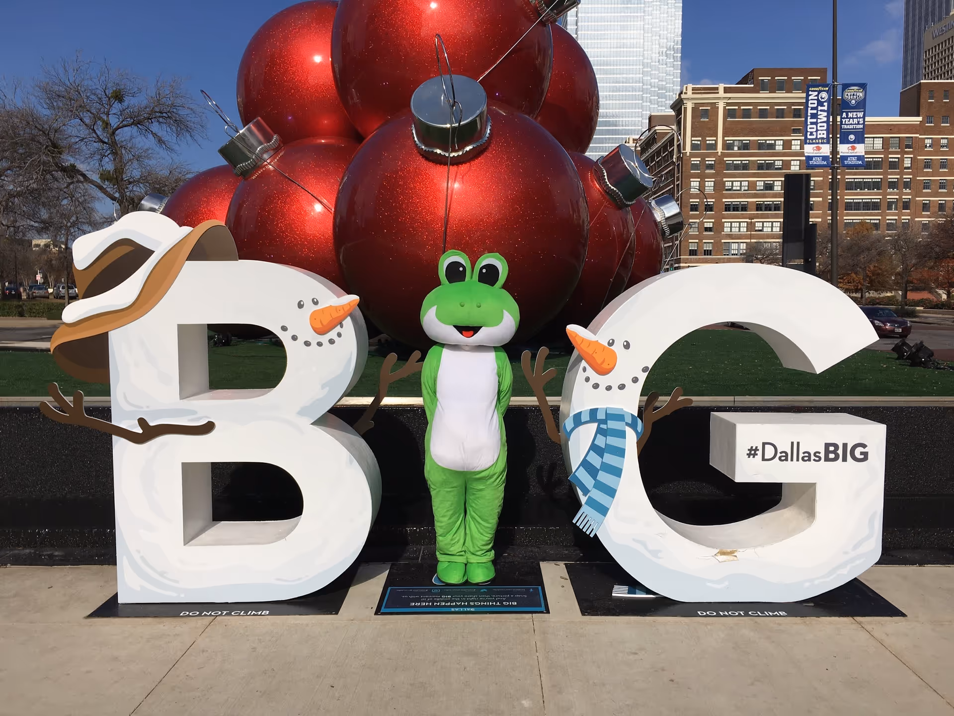 Outdoor display with oversized white letters, a green frog mascot, and festive red ornaments.