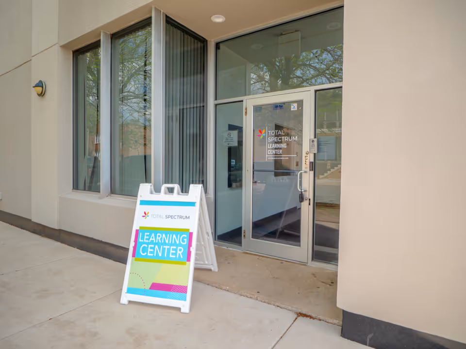 Front entrance of Total Spectrum facility with glass doors and a colorful Learning Center sign.