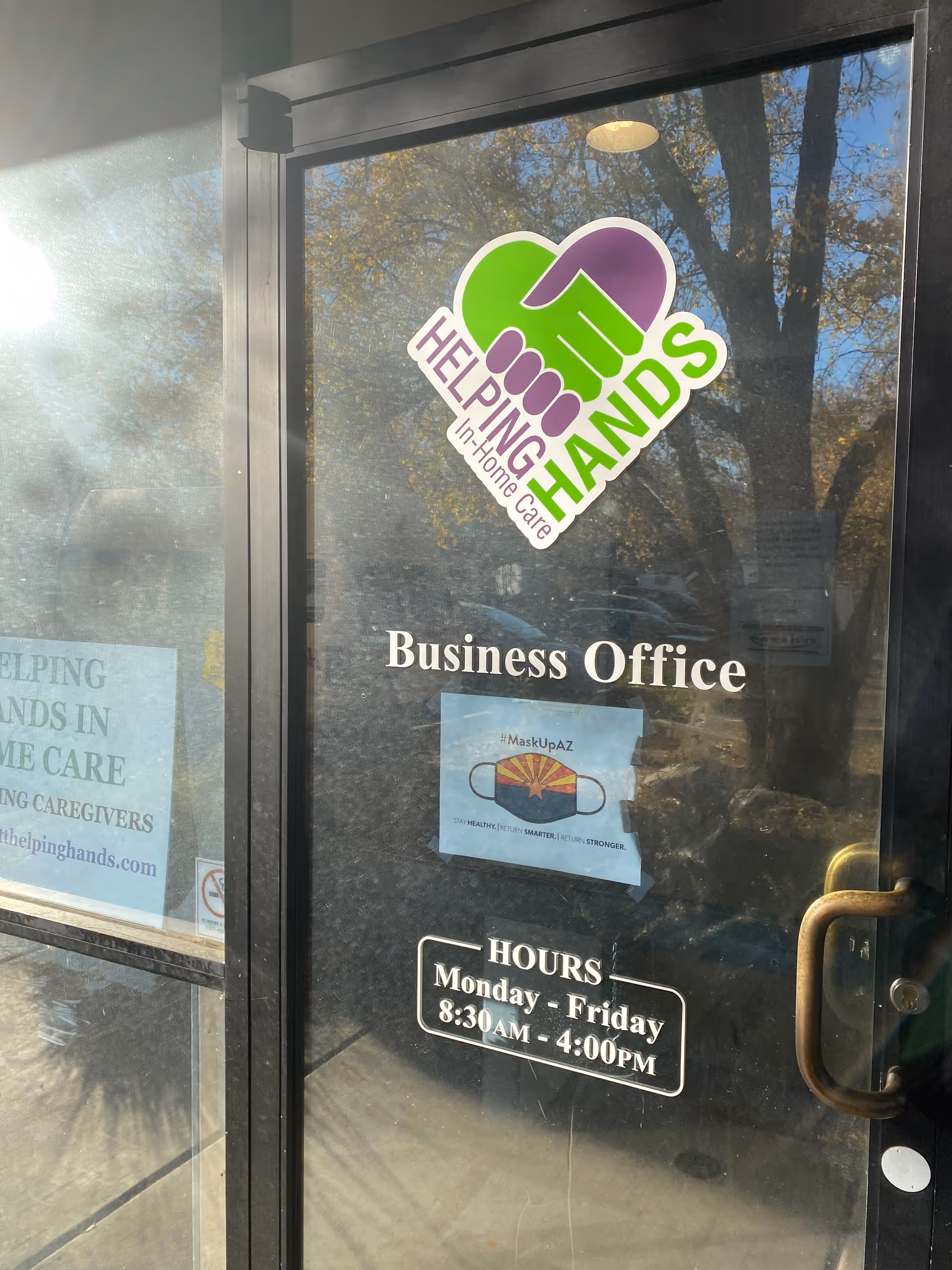 Glass door displays the Helping Hands logo and business office hours.