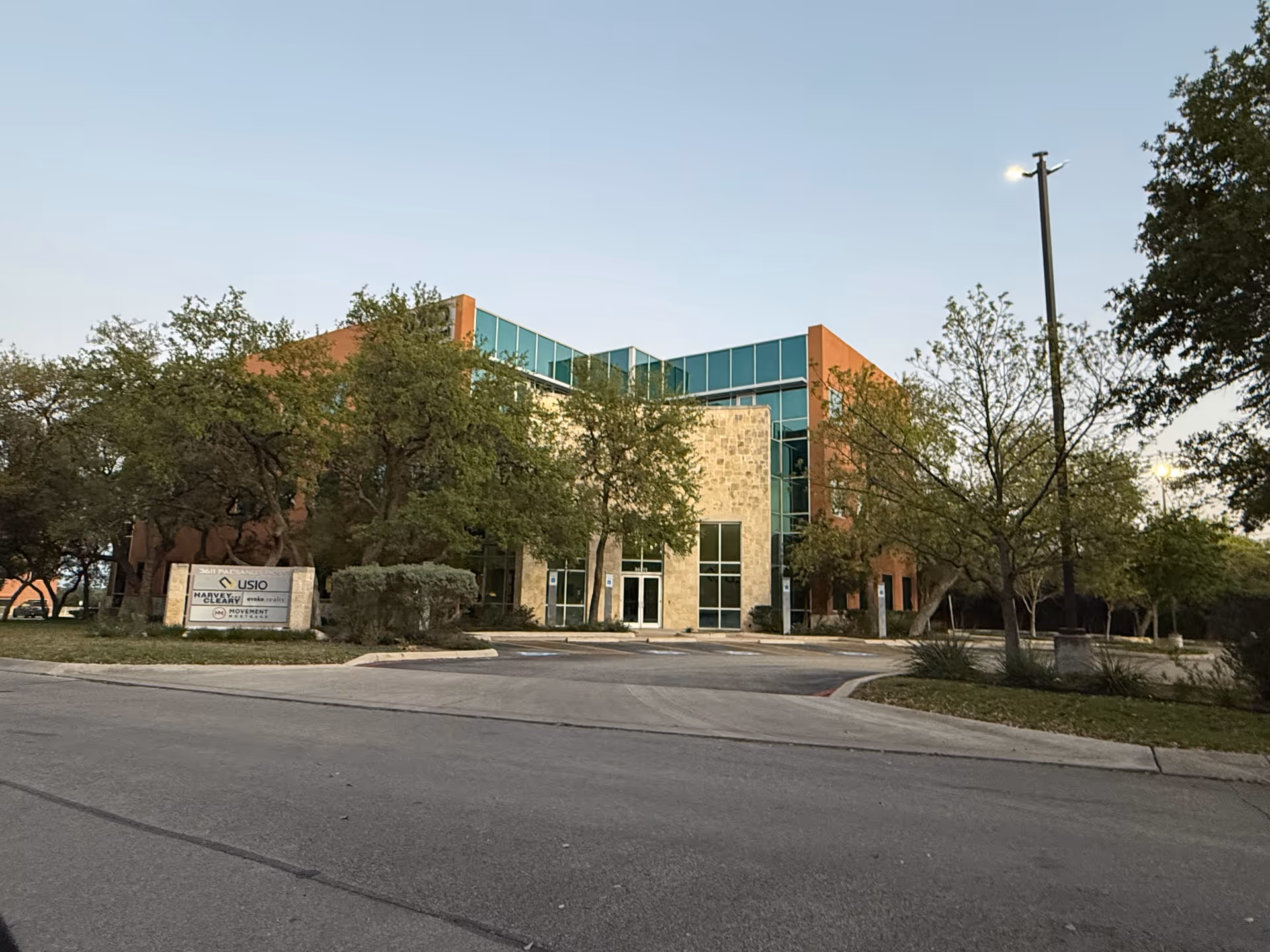 A modern senior living facility exterior with glass facade and surrounding trees.