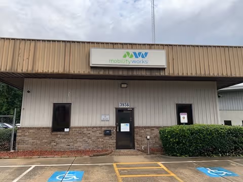 Front view of MobilityWorks facility with sign, parking lot, and handicapped spaces.