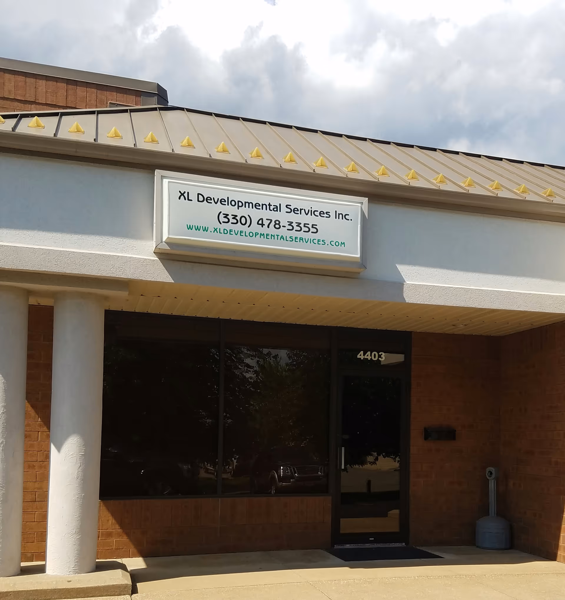 Front exterior of XL Developmental Services building with sign and glass entrance door.
