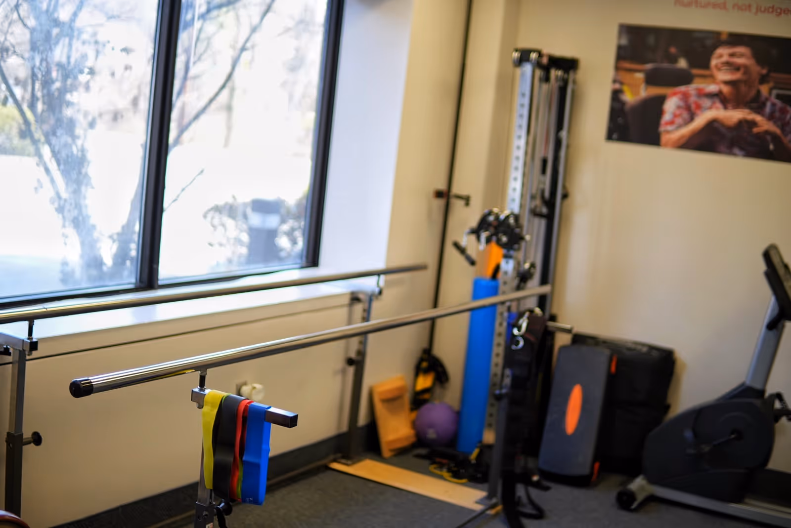 Indoor gym area with a barbell, resistance bands, and workout equipment near a large window.