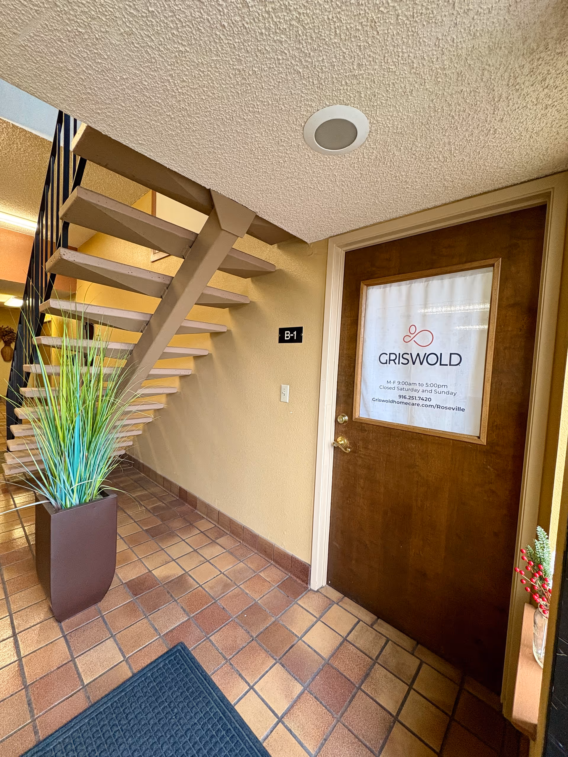 Interior hallway with staircase, potted plant, and a door labeled Griswold.