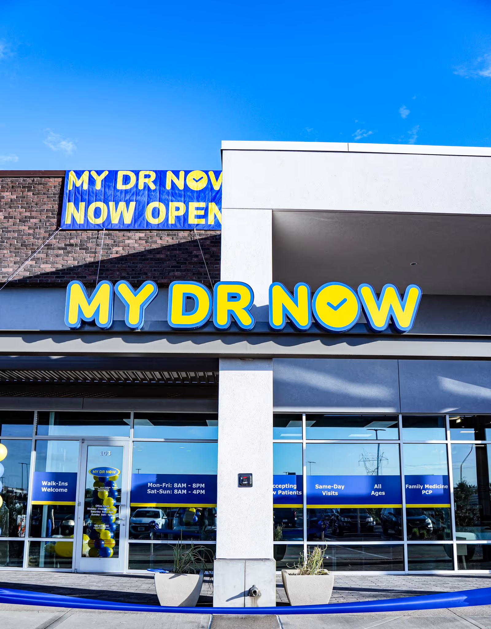 Exterior view of a storefront with MY DR NOW sign and NOW OPEN banner