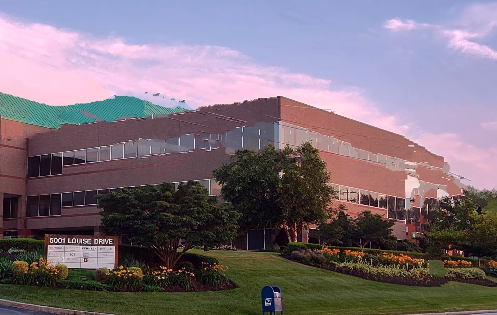 Exterior view of a large brick medical building with landscaped lawn and trees.