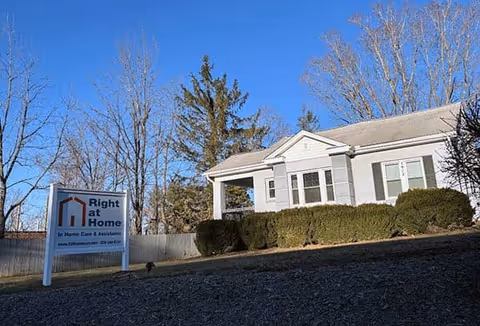 A single-story building with a Right at Home sign and trimmed hedges in front.