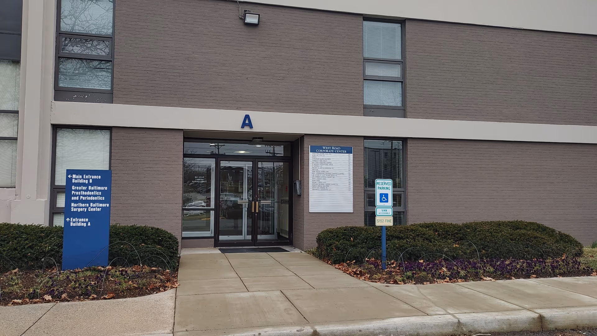 Senior living facility entrance with glass doors, a large A sign, and blue informational signs.