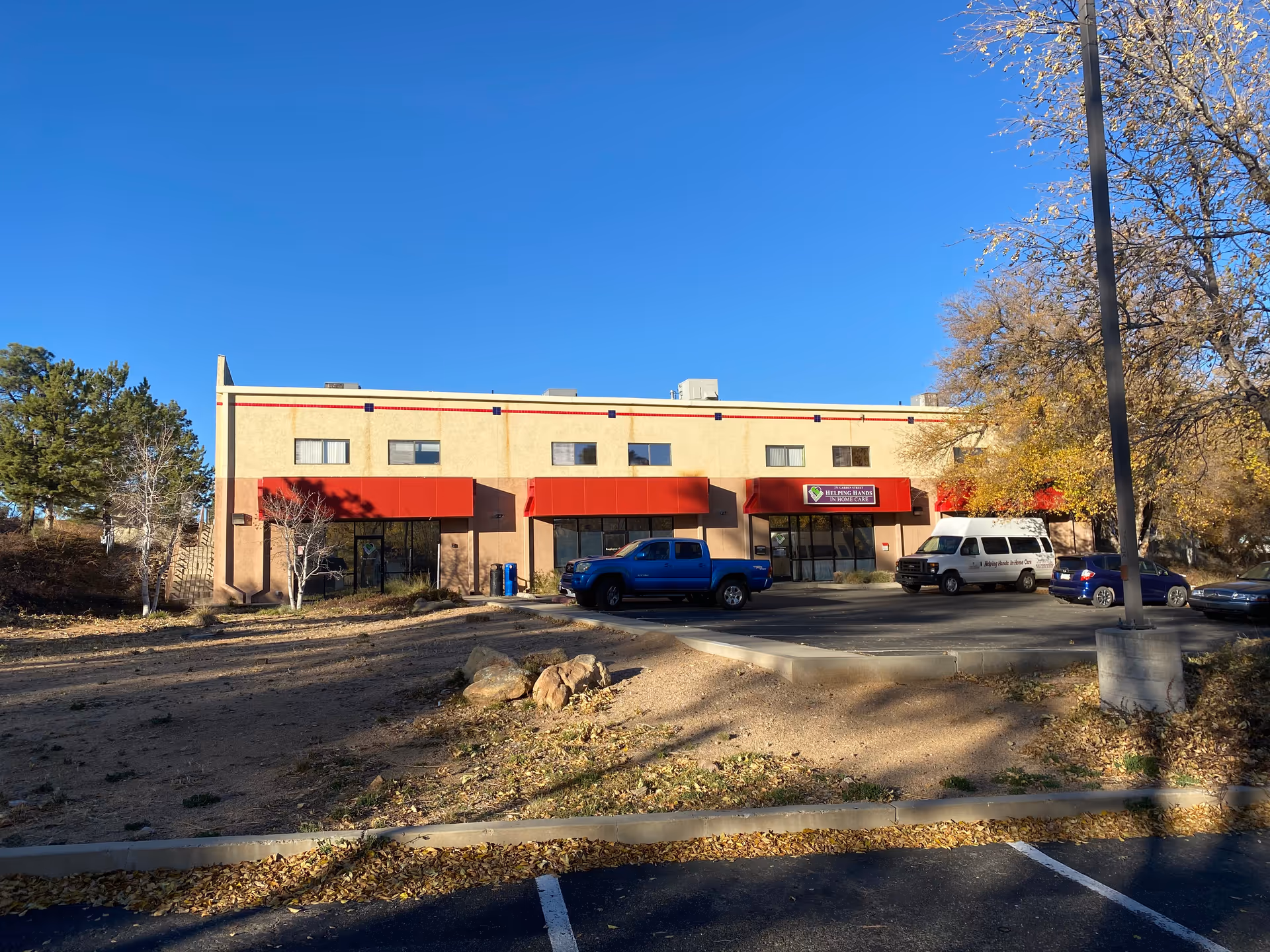Exterior of a building with red awnings and parked cars.