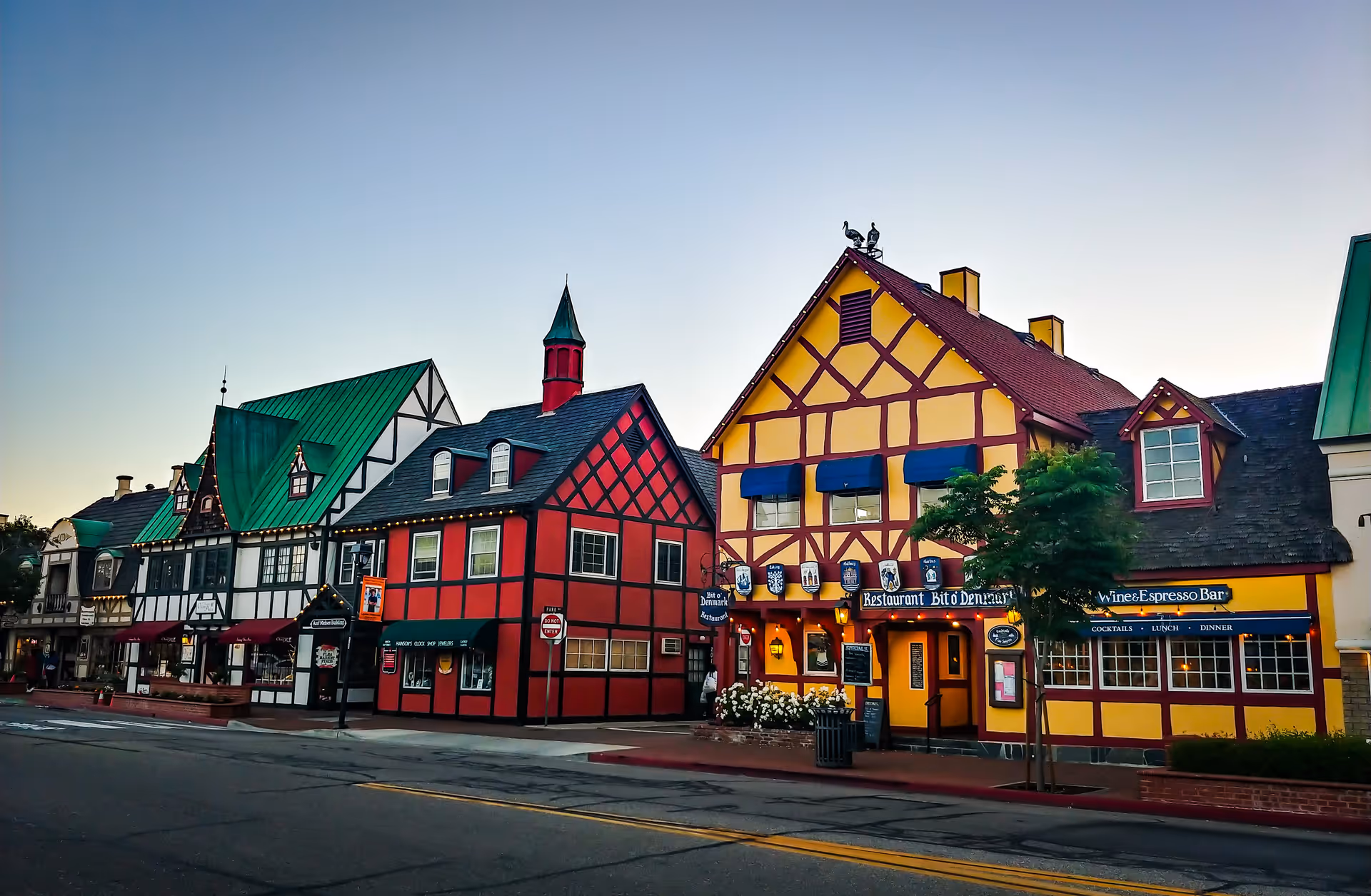 Colorful timber-framed storefronts line a quiet street at dusk.