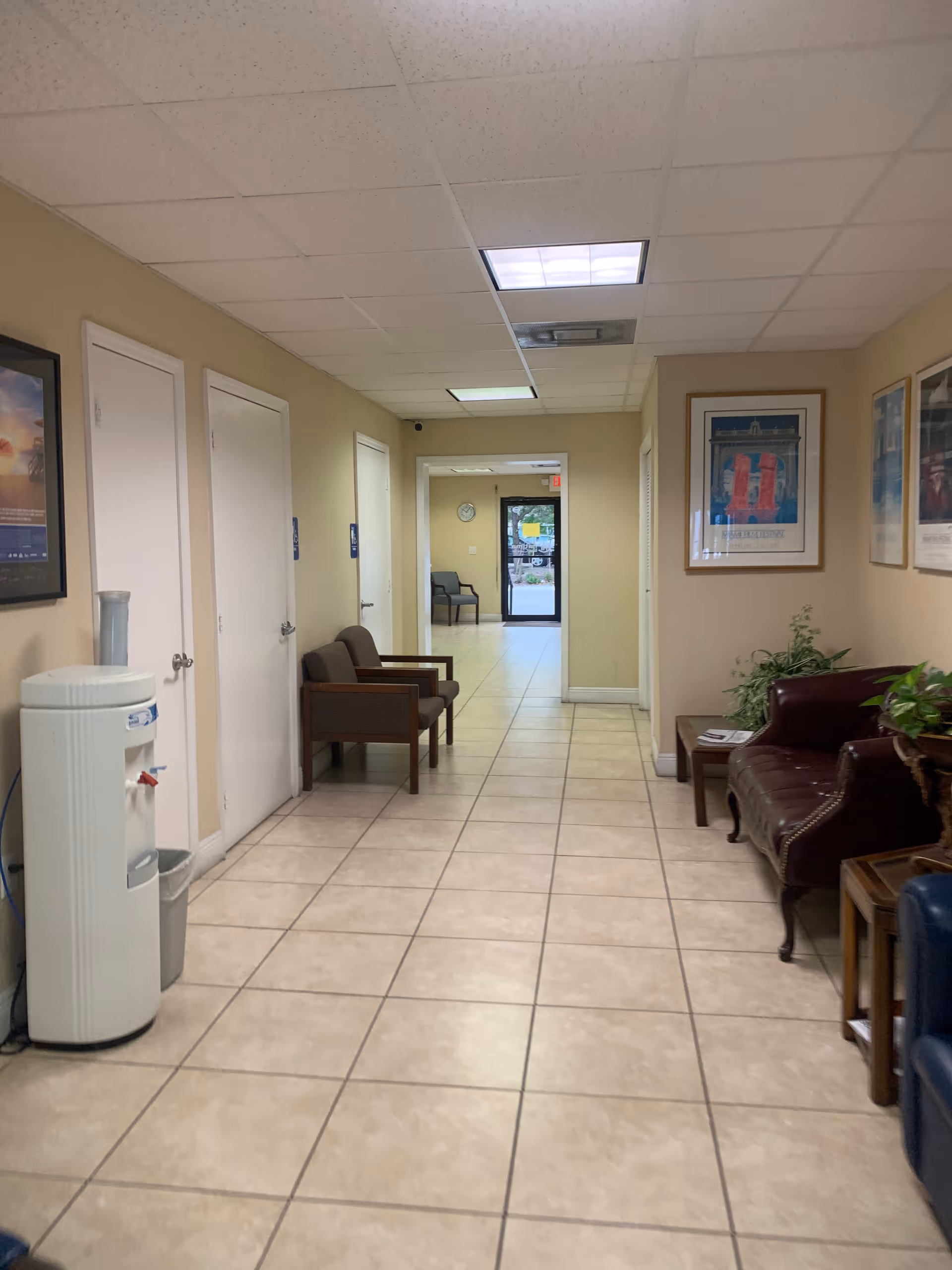 Long, well-lit hallway in a senior living facility with seating and a water cooler.