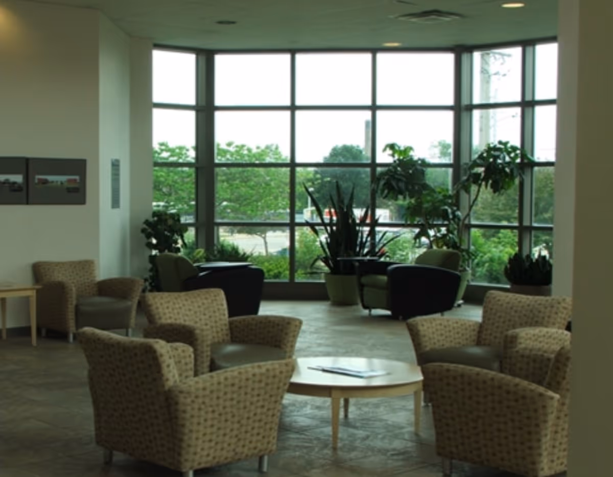 Bright facility lobby with seating, tables, and a large window wall.