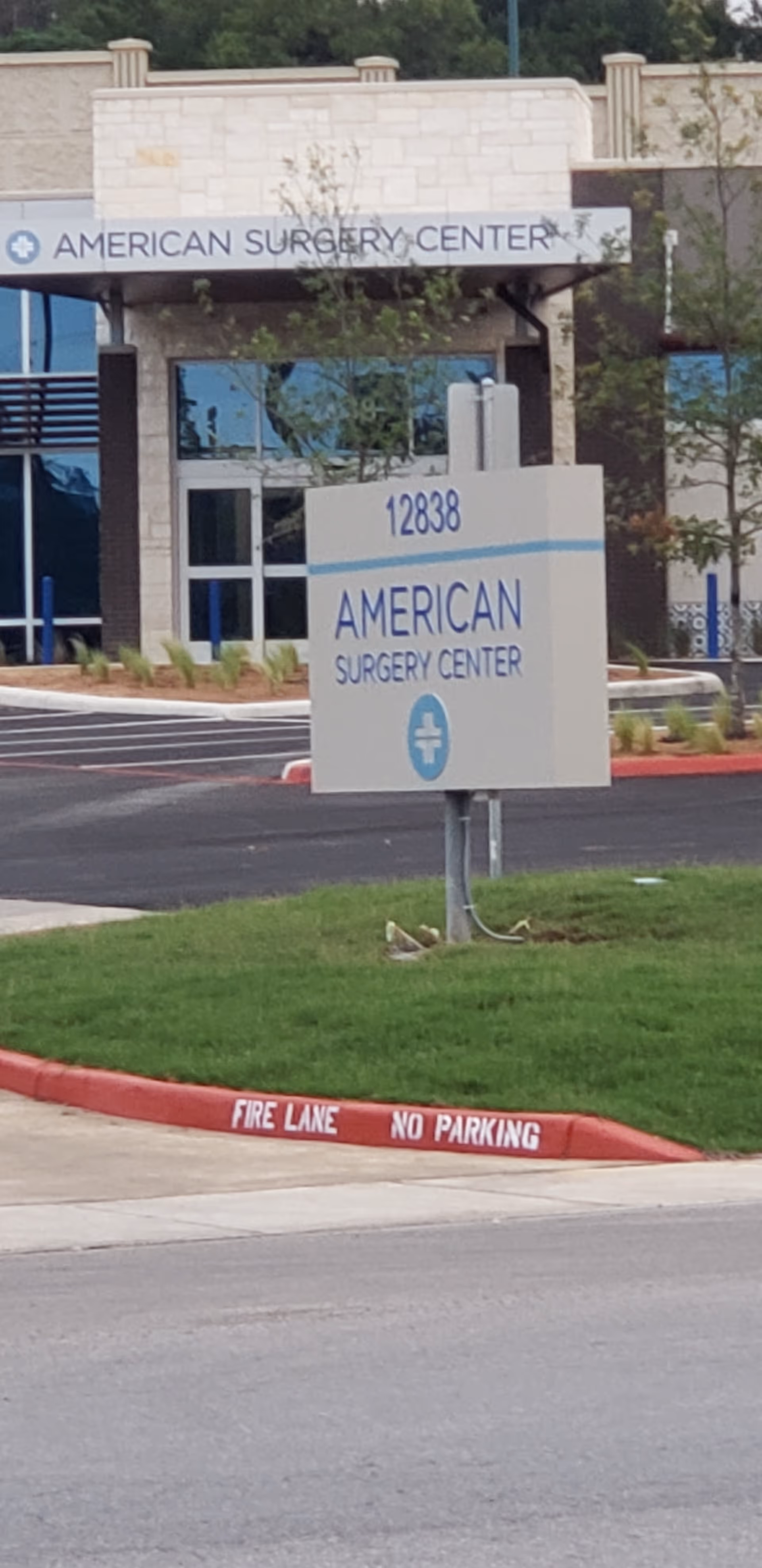 Exterior view of American Surgery Center entrance with sign and parking lot.