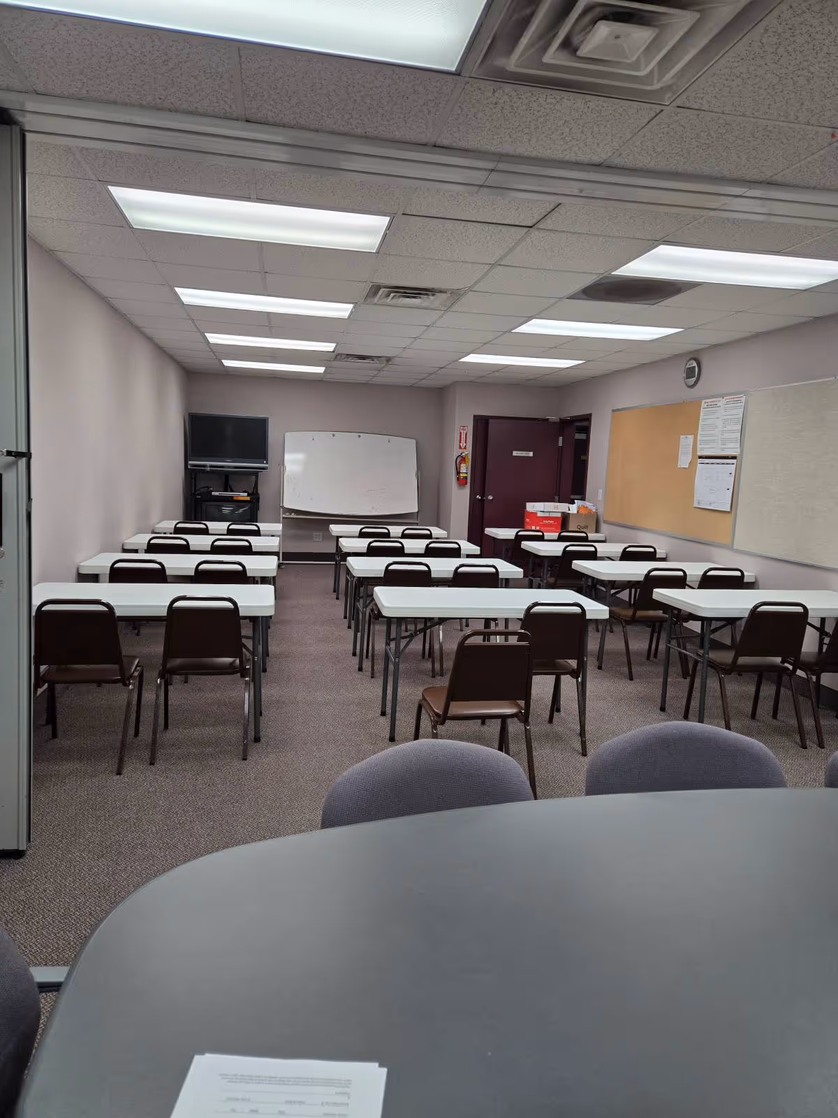 Classroom-style room in Visiting Angels Senior Home Care with rows of tables and chairs.
