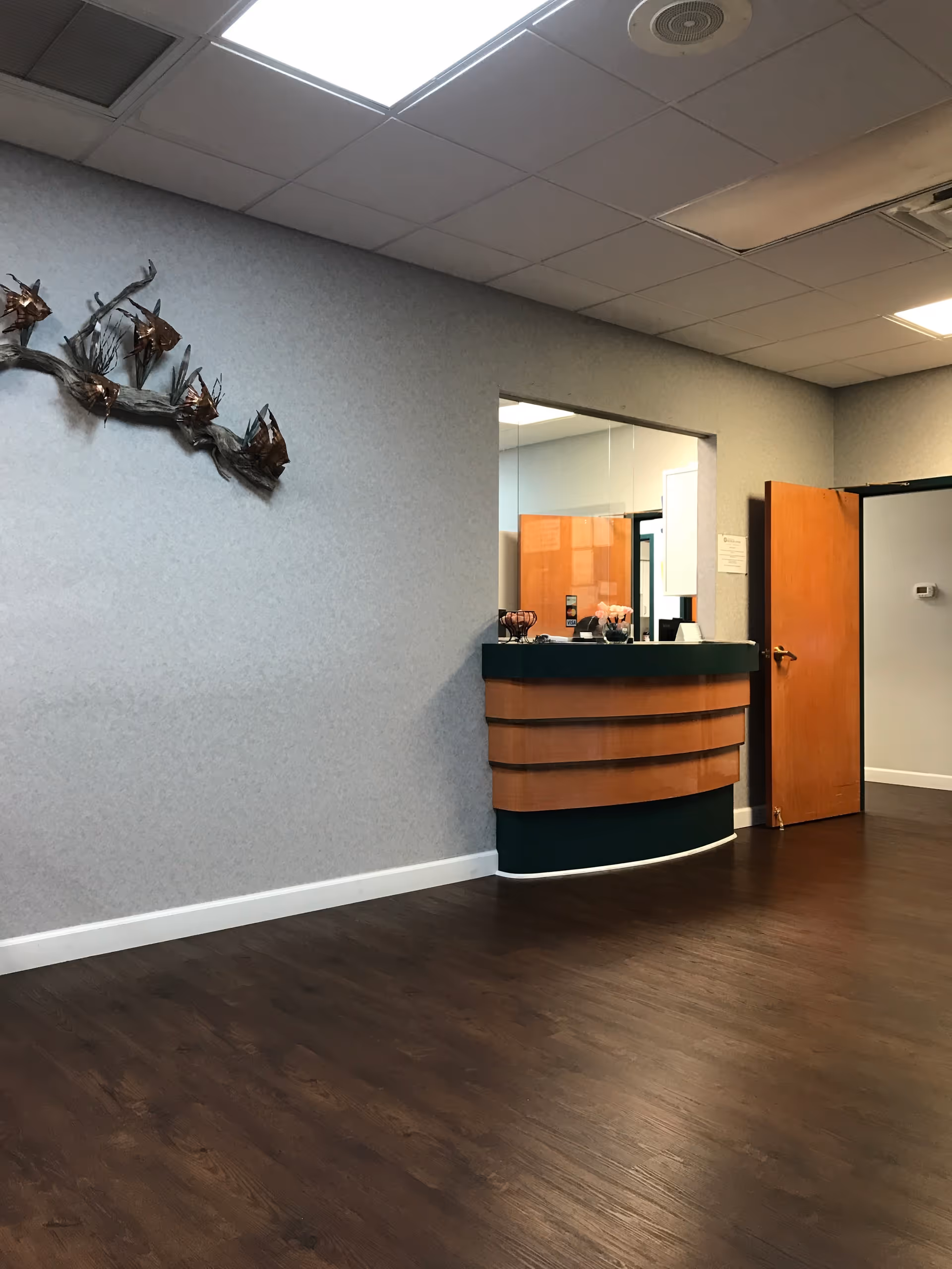 Reception desk in a spacious, empty lobby with wood floors and gray walls