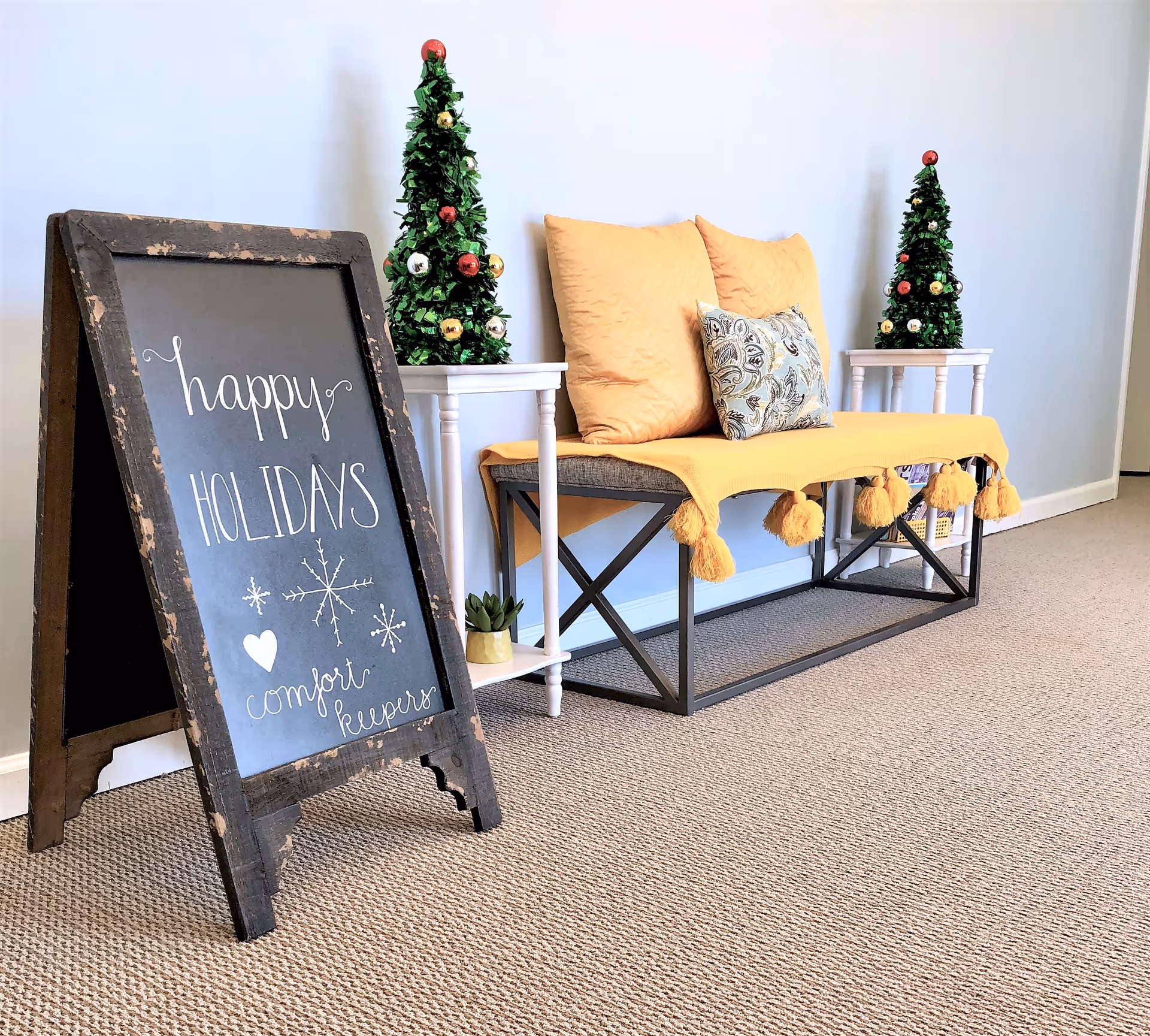 Cozy interior seating area with a chalkboard sign, holiday decor, and small Christmas trees.