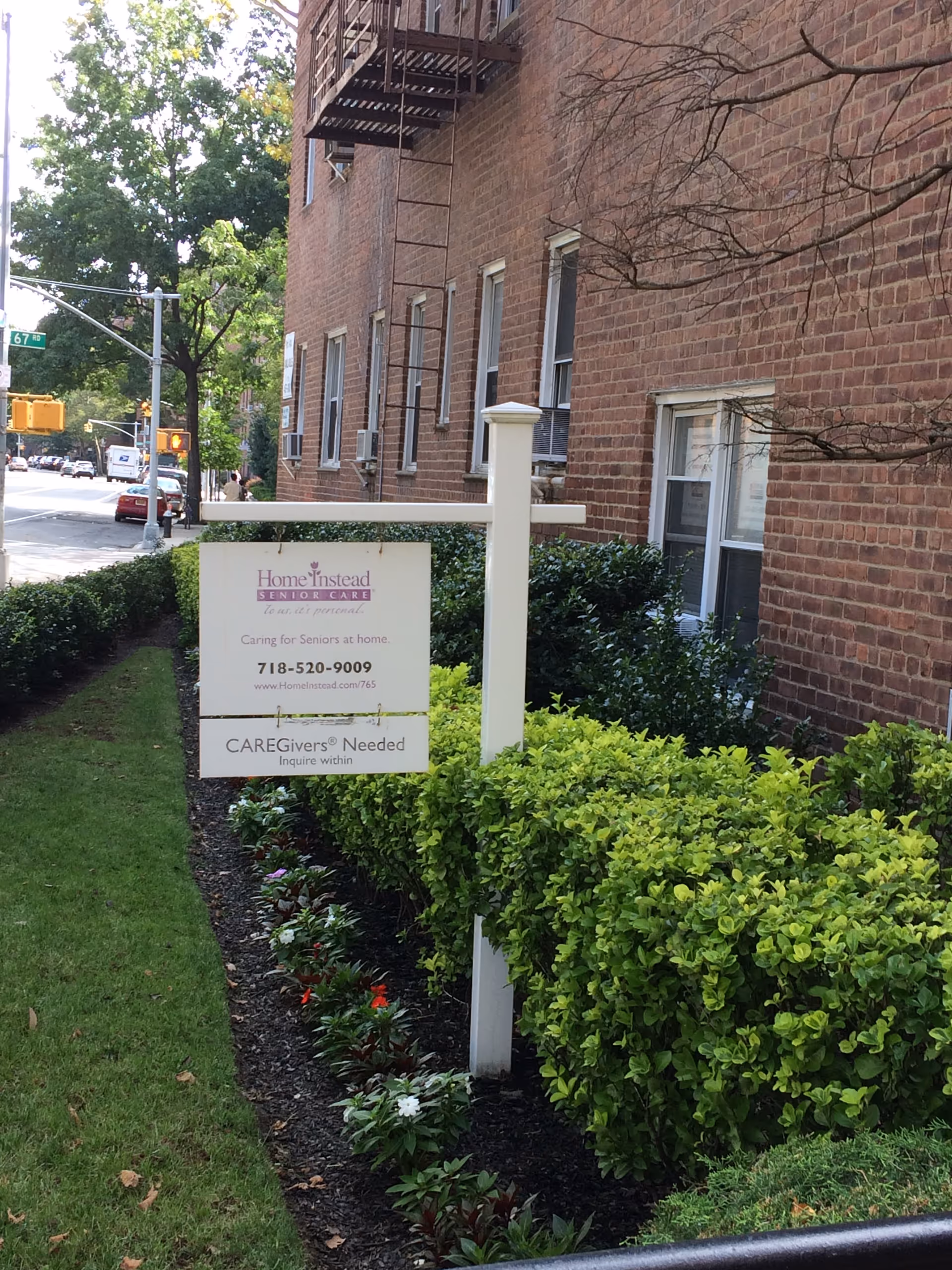 Brick building exterior with a Home Instead Senior Care sign and neatly trimmed hedges.