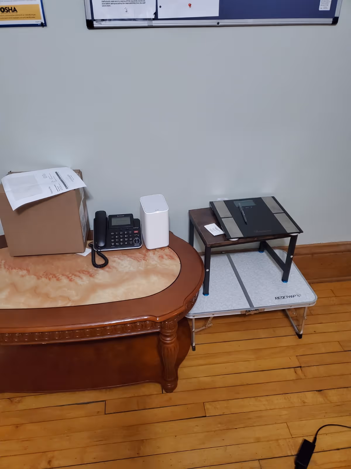 Indoor reception desk with landline phone, cardboard box, and small platform.