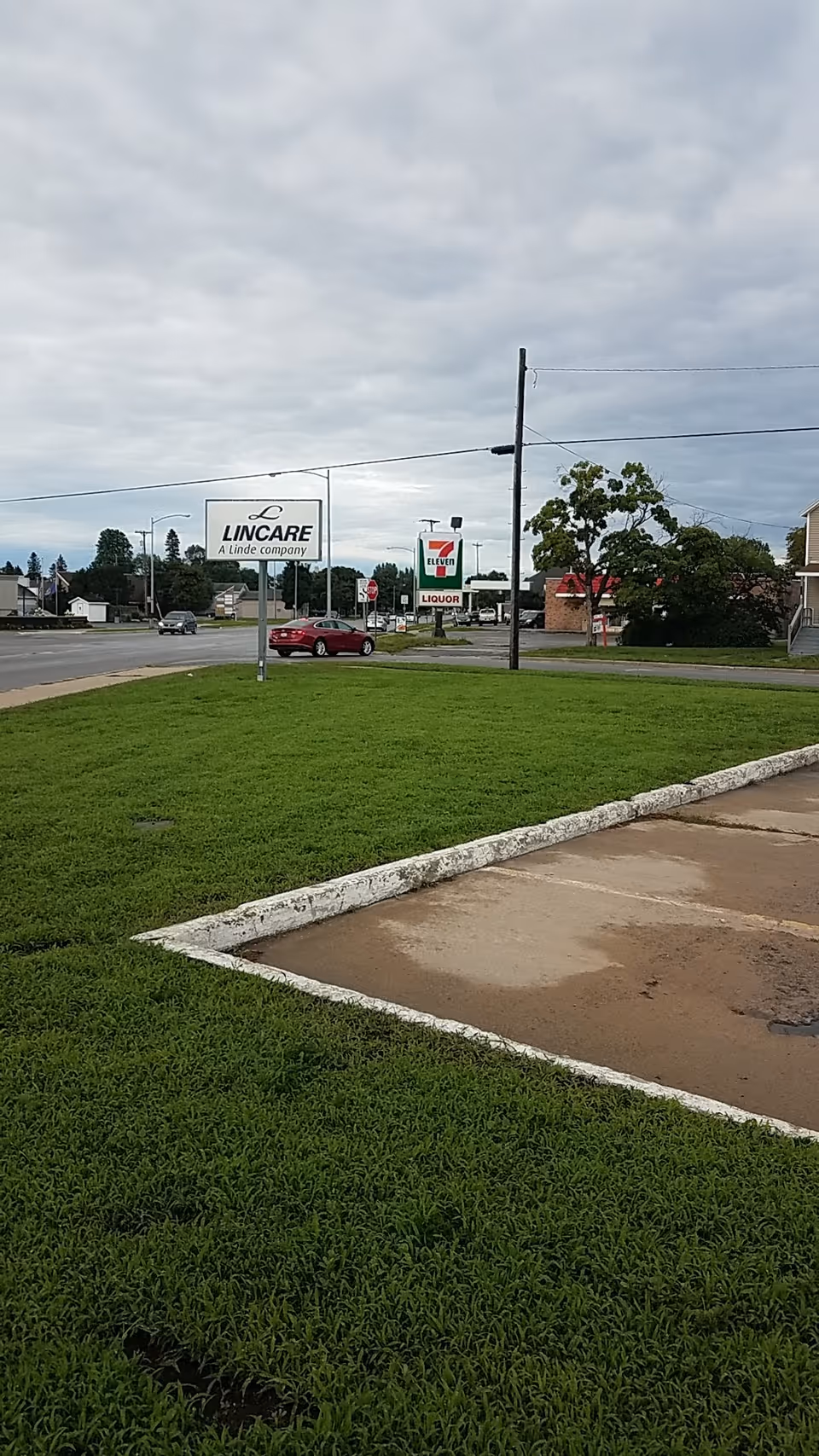 LINCARE sign on a street with a grassy lot and 7-Eleven in the background.