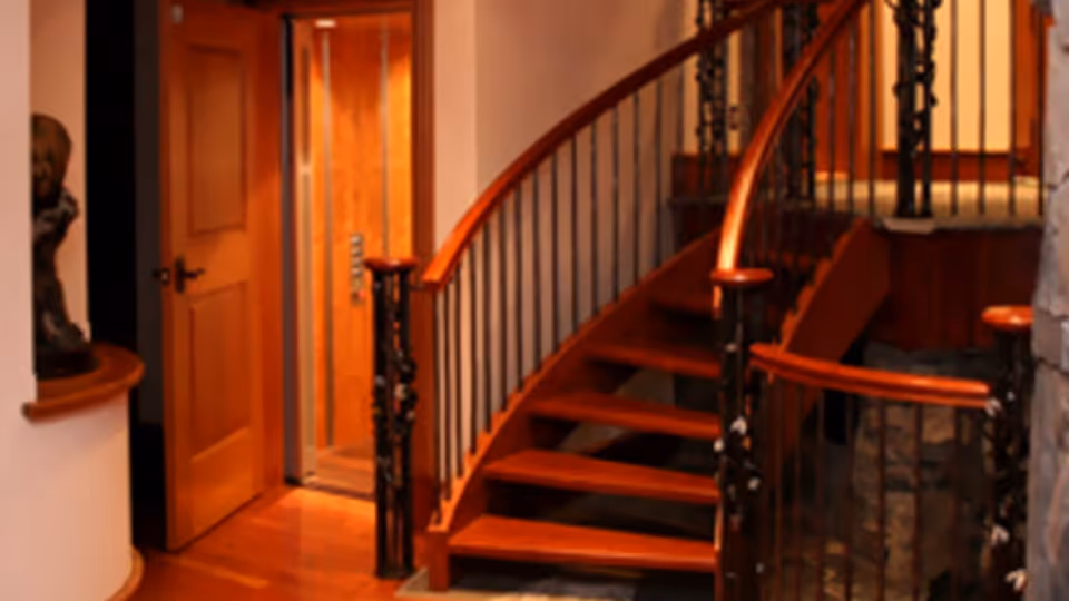 Warm interior hallway featuring a curved wooden staircase and black iron balusters.