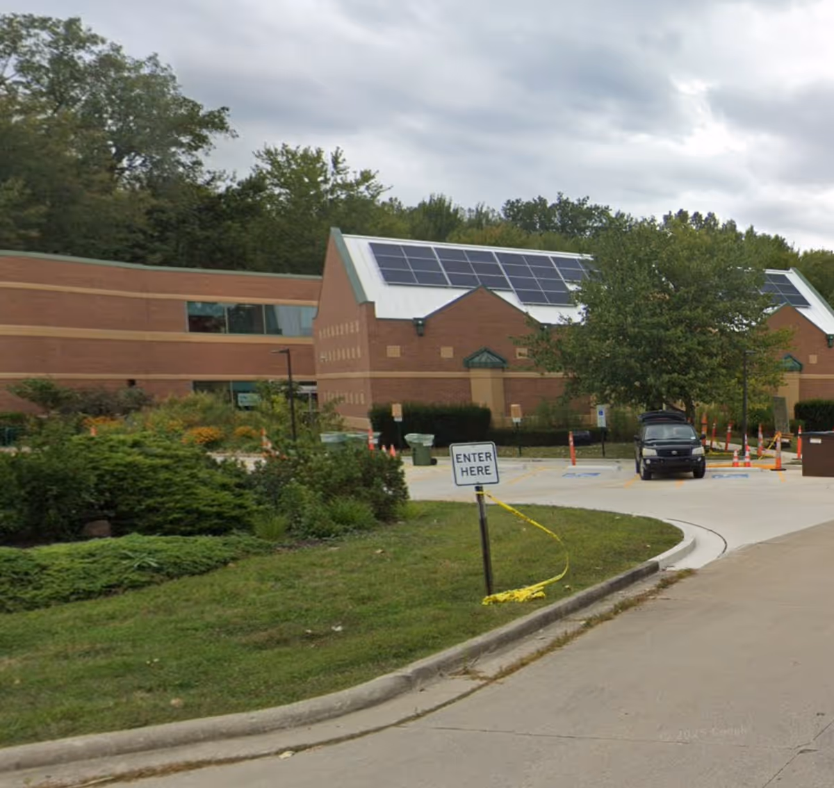 Exterior view of a brick senior living facility with solar panels and an entrance driveway.