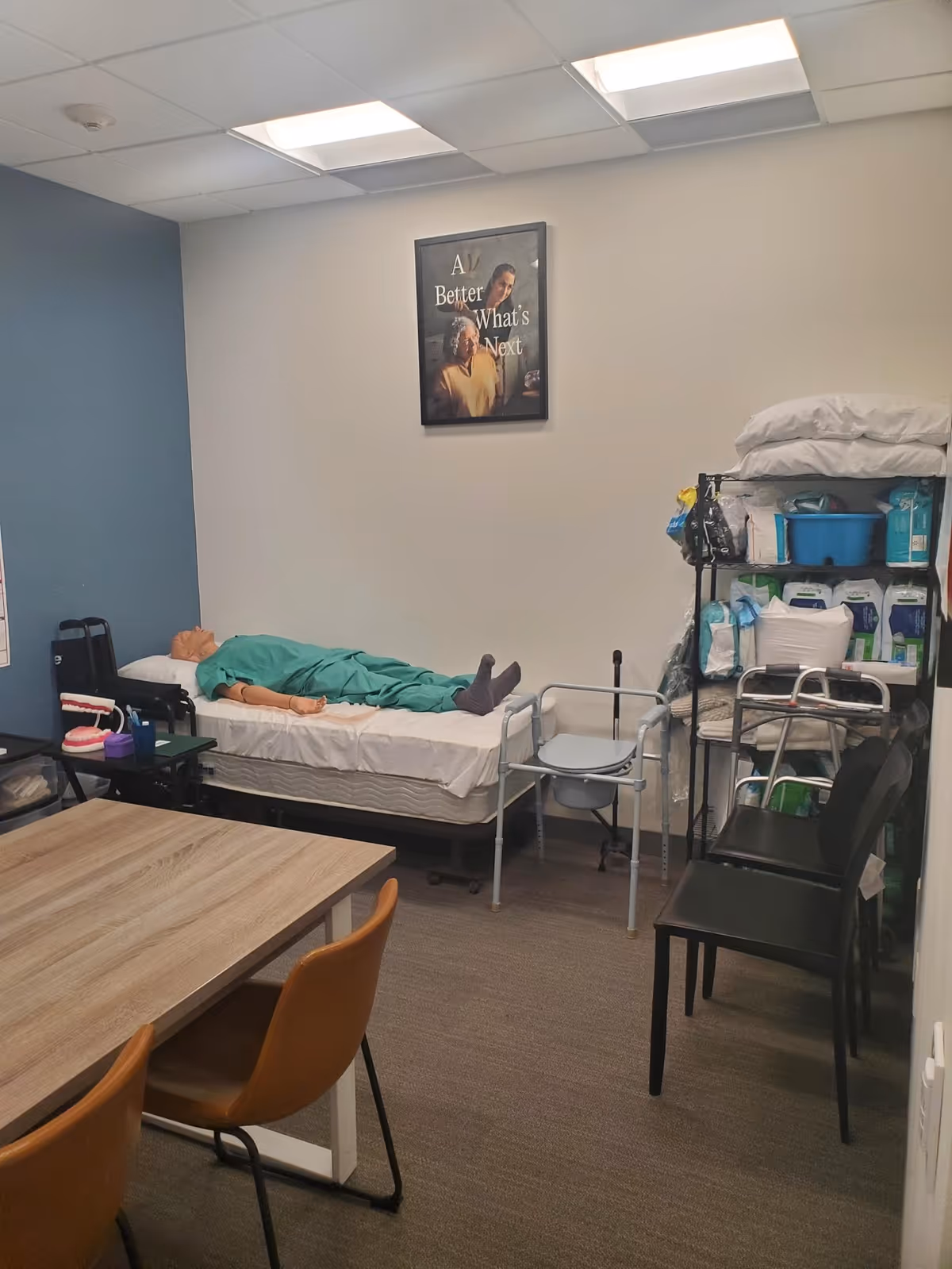 A patient care room with a bed, medical supplies, and chairs in a senior facility.