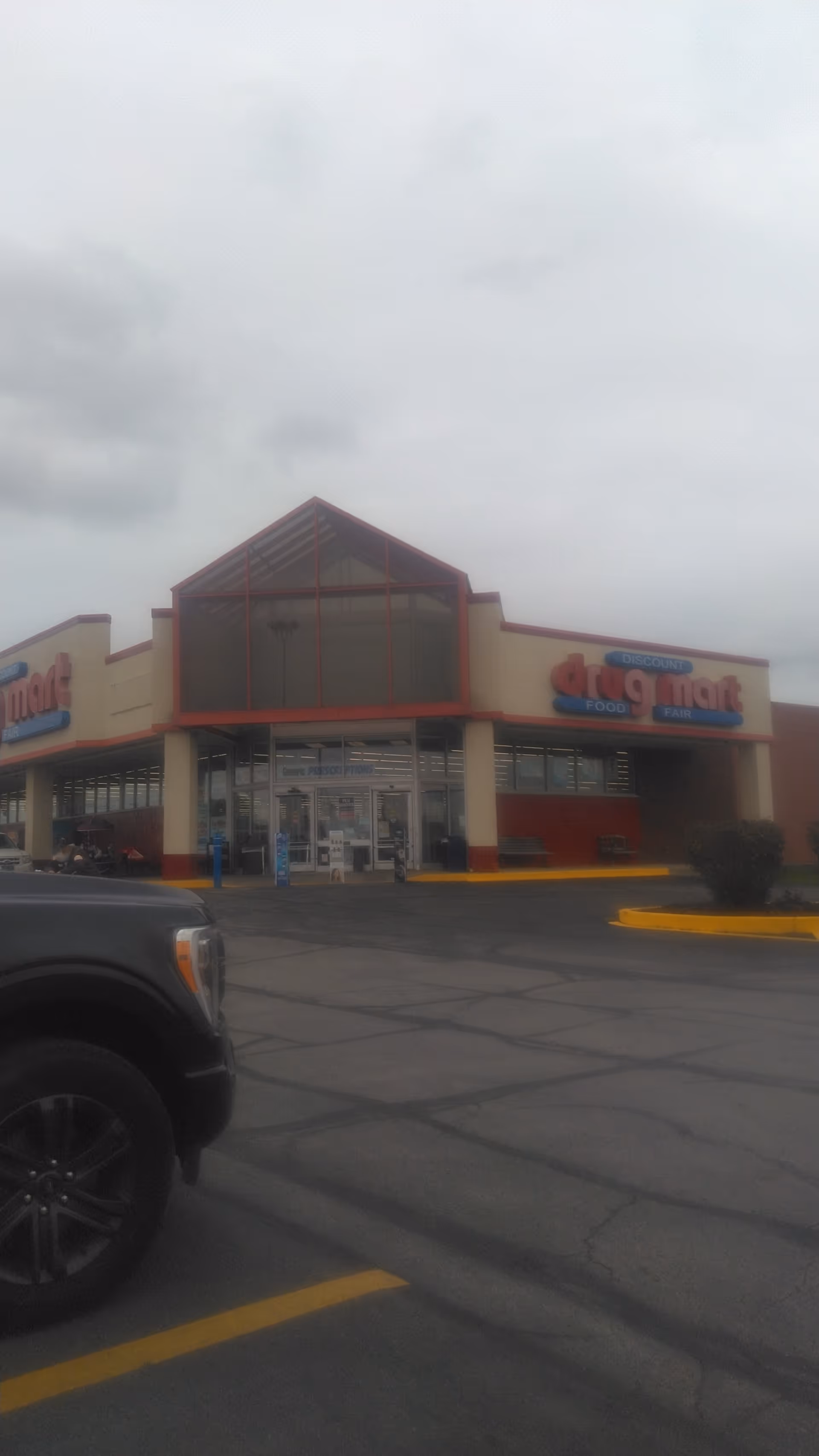 Discount Drug Mart storefront with glass entrance in a parking lot.