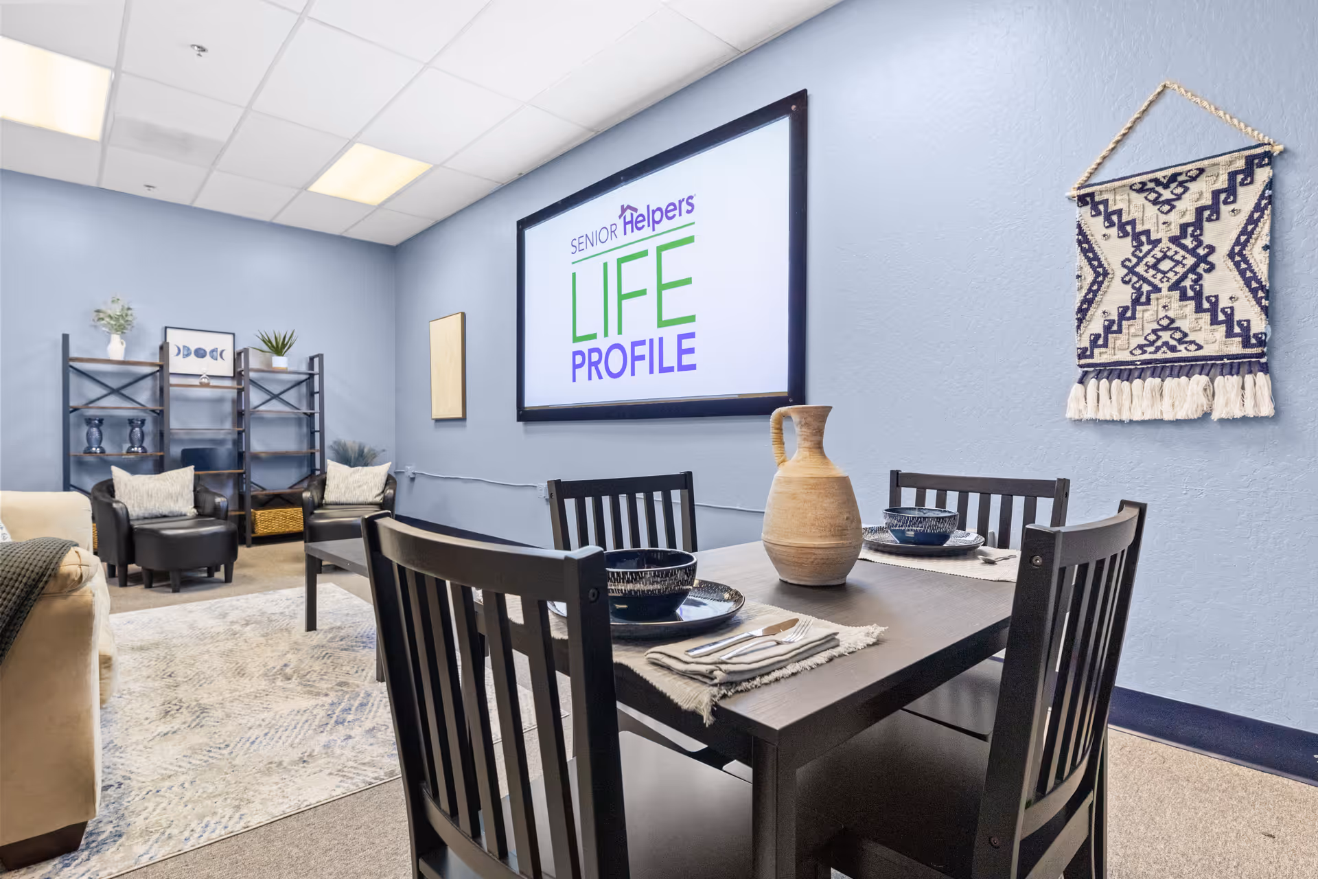 A dining table set for four in a blue-walled senior living common area.