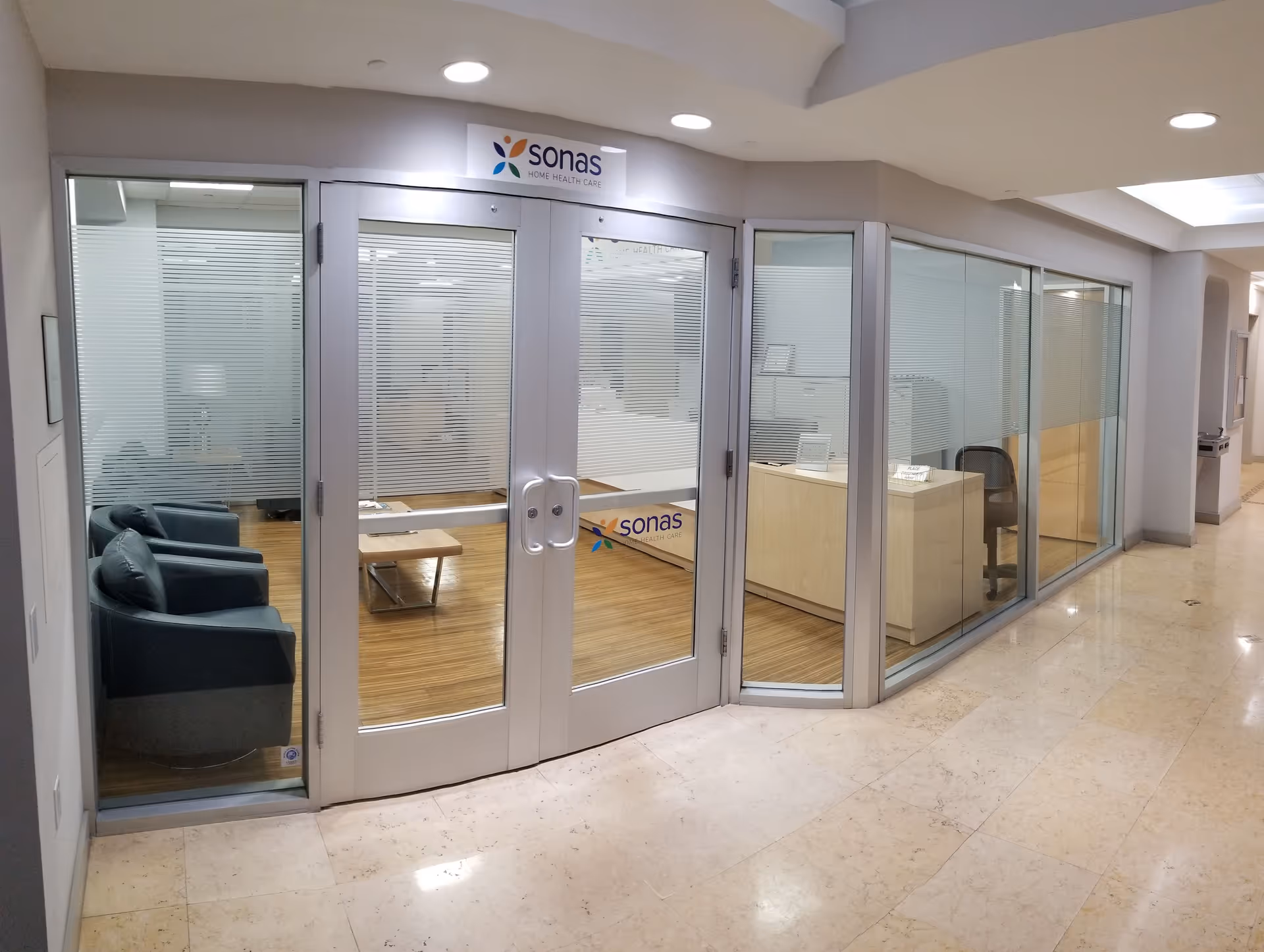 Glass-walled interior lobby with seating and a front desk behind curved doors.