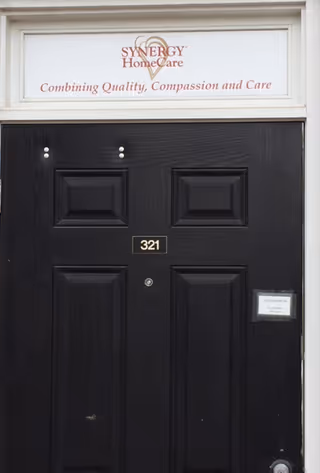 Black front door with Synergy HomeCare sign above and the number 321.