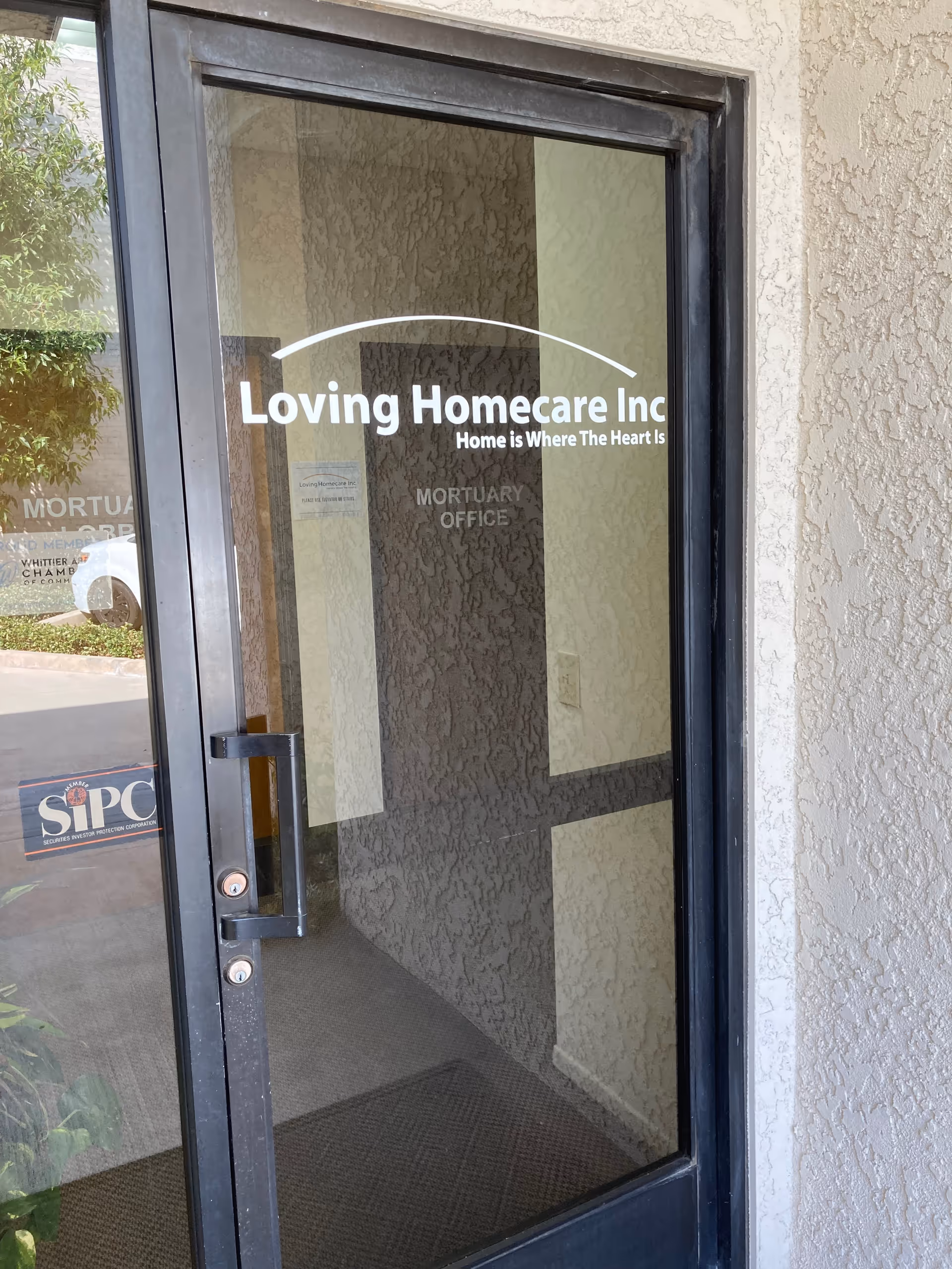 Glass door displays Loving Homecare Inc signage at the exterior building entrance.