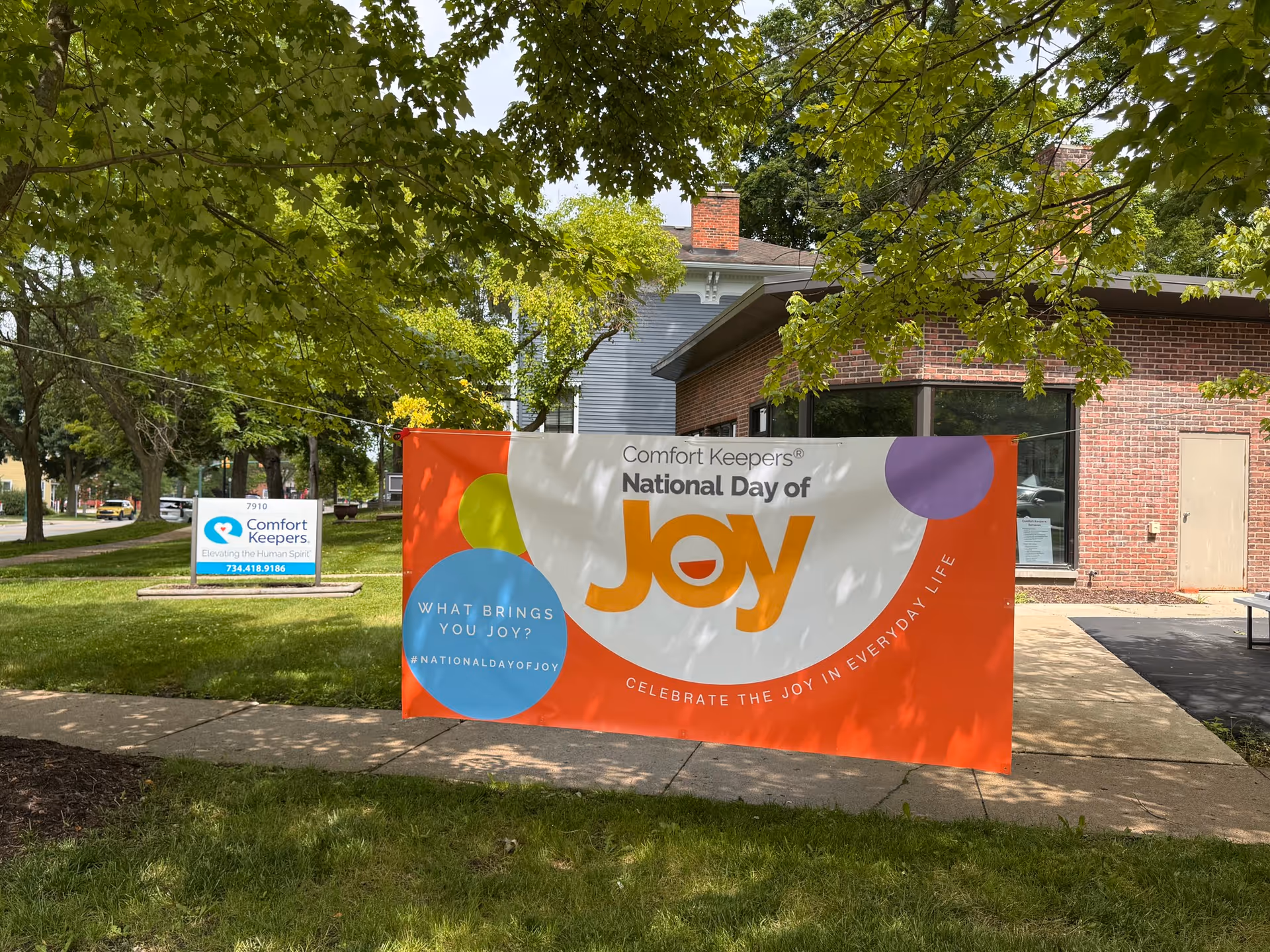 Outdoor view of Comfort Keepers building with a large Joy banner on the lawn.