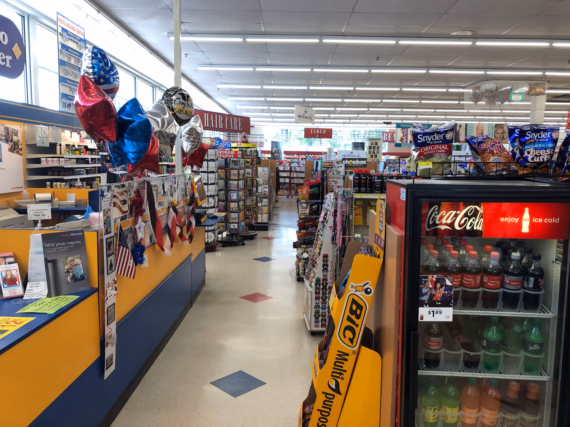 Inside Discount Drug Mart, bright interior with aisles, shelves, and a Coca-Cola cooler.