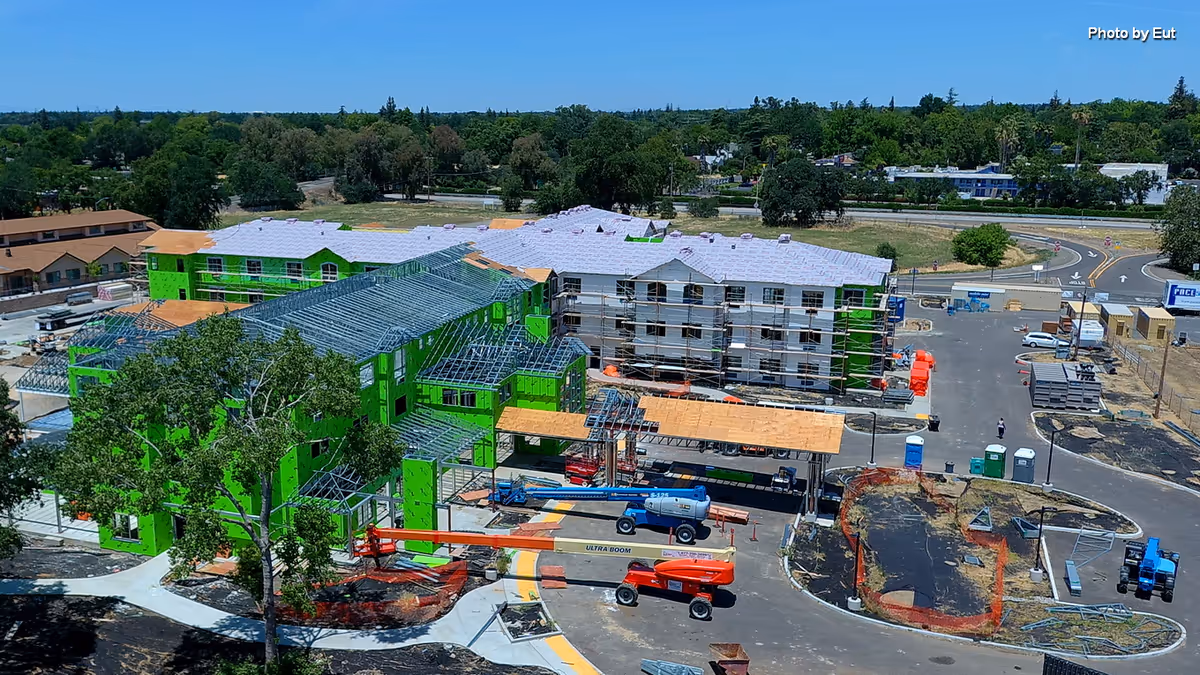 A construction site with green-framed buildings under development and heavy equipment.