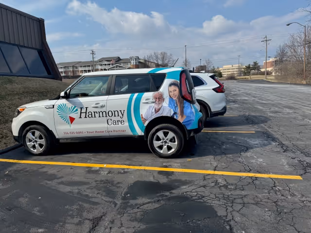 Harmony Care vehicle with logo and resident imagery parked in a cracked, empty parking lot