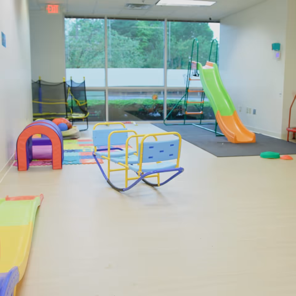 Bright indoor playroom with colorful slide, soft mats, and kid-friendly seating.
