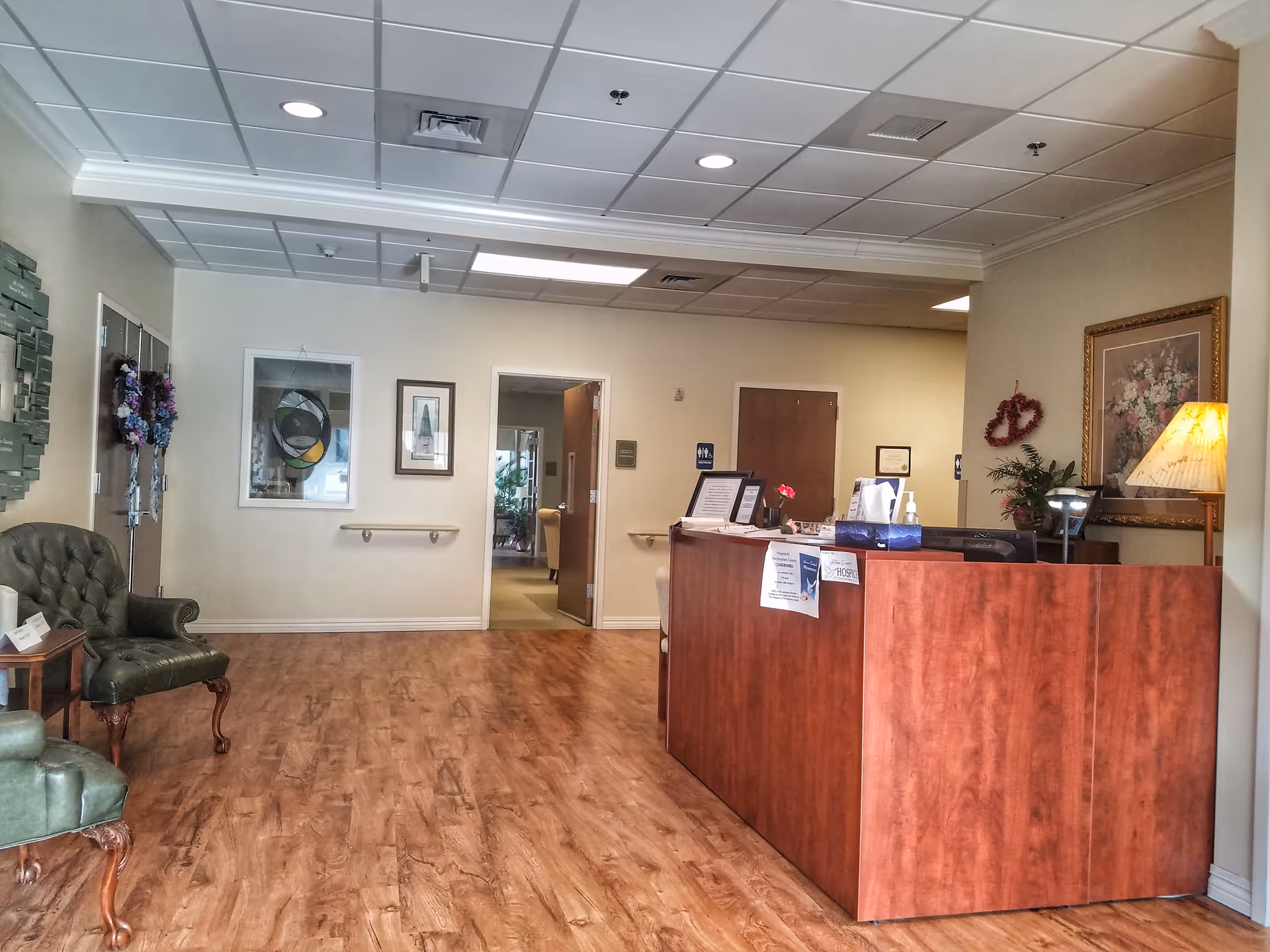 Reception desk in a senior living facility lobby with seating area and artwork.